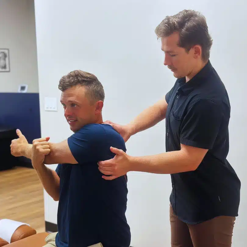 Chiropractor guiding patient through shoulder mobility rehab to improve flexibility and reduce tension.