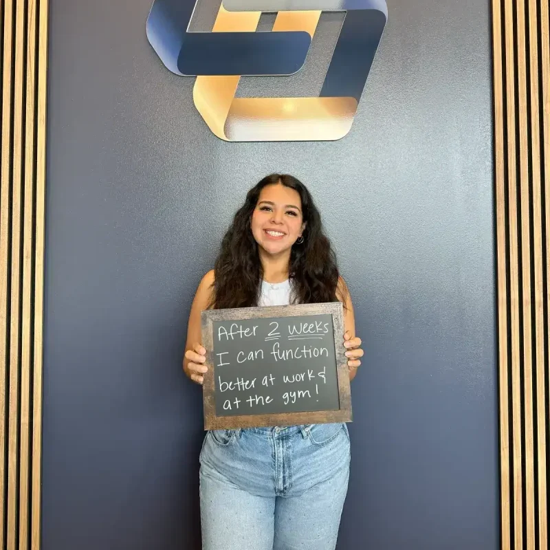 Male patient at Limitless Chiropractic, your chiropractor in North Fort Worth, holding a sign: "My energy is back! I can play with my kids again!" - also serving Alliance.